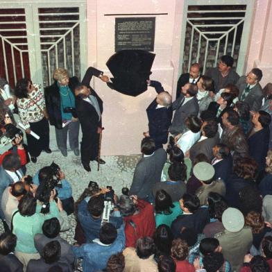 Governador Synval Guazzelli e o poeta Mario Quintana durante o  descerramento da placa de reinauguração da CCMQ. Mais de mil pessoas participaram dia 25/09/1990 da reabertura da Casa de Cultura Mario Quintana. O poeta Mario Quintana foi a grande estrela da festa e falou do que mais sabe: de sua poesia e de Porto Alegre.Desde o início da tarde a multidão aguardava a abertura do prédio do antigo Hotel Magestic, residência do poeta por mais de dez anos. A inauguração só teve início oficialmente quando chegaram os convidados especiais por volta das 18h.Na década de 70 o hotel foi desativado. A partir de 30/08/1985, quando o prédio passou a integrar o patrimônio histórico e artístico nacional, foi que teve início a luta pela transformação do hotel em casa de cultura. Nesse momento a Casa de Cultura já existia como órgão oficial, criado pela lei 7803, de 08/07/1983. #ENVELOPE: 96038<!-- NICAID(1820132) -->