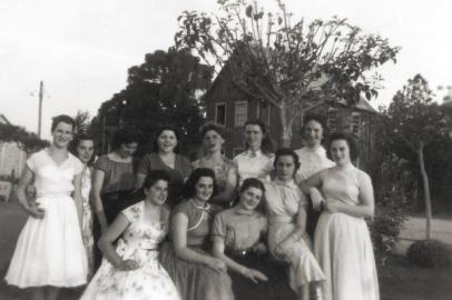 Maria de Lourdes Ildegar Jung e um grupo de amigas na Praça de Santa Lúcia do Piaí por volta de 1960. A partir da esquerda, em pé, Neusa Mielke, Clarice Daneluz, Catarina Cavalli, Zaira Scalcon, Nuely Communello, Maria de Lourdes Trapp, Ildegar Jung, Dirce Zini, Iracema Daneluz, Lisete Scalcon, Loirena Tomazzelli e Leonice Daneluz. 