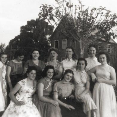 Maria de Lourdes Ildegar Jung e um grupo de amigas na Praça de Santa Lúcia do Piaí por volta de 1960. A partir da esquerda, em pé, Neusa Mielke, Clarice Daneluz, Catarina Cavalli, Zaira Scalcon, Nuely Communello, Maria de Lourdes Trapp, Ildegar Jung, Dirce Zini, Iracema Daneluz, Lisete Scalcon, Loirena Tomazzelli e Leonice Daneluz. 