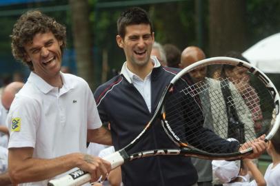 Tennis world number one, Serbian Novak Djokovic (R), and former world number one, Brazilian Gustavo Guga Kuerten, joke after the inauguration of a tennis court at Rocinha slum, in Rio de Janeiro on November 16, 2012, Brazil. AFP PHOTO / CHRISTOPHE SIMON<!-- NICAID(8820378) -->