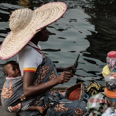 A picture taken on March 2, 2019 shows a woman selling daily items on a boat in the Makoko waterfront community in a polluted lagoon in Lagos, Africas biggest megalopolis in Nigeria. - The sprawling community began in the 19th century as a fishing village for immigrants who settled on the waters edge. As more arrived and land became rare, people started to move out onto the water. Over time, Makoko became a floating realm of perhaps a quarter of a million people, although the real number is anyones guess. (Photo by YASUYOSHI CHIBA / AFP)<!-- NICAID(14392682) -->