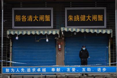 A security guard stands outside the Huanan Seafood Wholesale Market where the coronavirus was detected in Wuhan on January 24, 2020 - The death toll in Chinas viral outbreak has risen to 25, with the number of confirmed cases also leaping to 830, the national health commission said. (Photo by Hector RETAMAL / AFP)