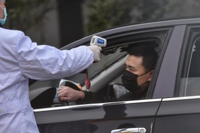  A police takes the temperature of a driver at a checkpoint on a street on the outskirts of Wuhan in China's central Hubei province on January 27, 2020, amid a deadly virus outbreak which began in the city. - China on January 27 extended its biggest national holiday to buy time in the fight against a viral epidemic and neighbouring Mongolia closed its border, after the death toll spiked to 81 despite unprecedented quarantine measures. (Photo by Hector RETAMAL / AFP)Editoria: HTHLocal: WuhanIndexador: HECTOR RETAMALSecao: diseaseFonte: AFPFotógrafo: STF