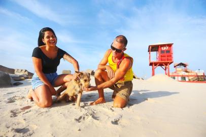  IMBÉ, RS, BRASIL,29/01/2020- Tatiele, Buzz e Gil se encontraram na manhã desta quarta-feira na frente do local onde o cãozinho foi salvo no Ano-Novo.  Na foto- Tatiele Fagundes, 32, dona do Buzz, o Buzz, cãozinho de 3 patas resgatado do mar de Imbe no Réveillon, e Gil Pereira, guarda-vidas que salvou o Cusco.(FOTOGRAFO: LAURO ALVES / AGENCIA RBS)