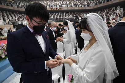 Couples wearing protective face masks attend a mass wedding ceremony organised by the Unification Church at Cheongshim Peace World Center in Gapyeong on February 7, 2020. - South Korea has confirmed 24 cases of the SARS-like virus so far and placed nearly 260 people in quarantine for detailed checks amid growing public alarm. (Photo by Jung Yeon-je / AFP)<!-- NICAID(14412658) -->