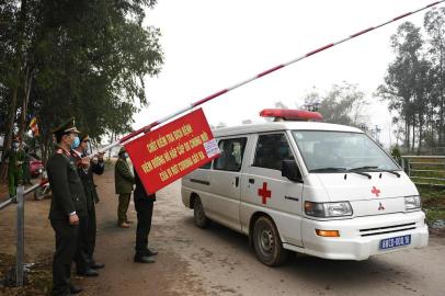 Police wearing protective facemasks amid concerns of the COVID-19 coronavirus allow an ambulance to pass through a checkpoint in Son Loi commune in Vinh Phuc province on February 13, 2020. - Villages in Vietnam with 10,000 people close to the nations capital were placed under quarantine on February 13 after six cases of the deadly new coronavirus were discovered there, authorities said. (Photo by Nhac NGUYEN / AFP)<!-- NICAID(14417700) -->