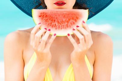  Summer colors. Girl holding slice of watermelon on the beach with red painted nails.Fonte: 164420140<!-- NICAID(14421858) -->