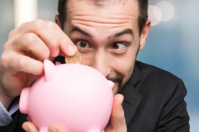 Businessman putting money in his piggy bankPORTO ALEGRE, RS, BRASIL,18/02/2020- Cofrinho, porquinho, dinheiro, economia. Foto: Minerva Studio / stock.adobe.comFonte: 208781756