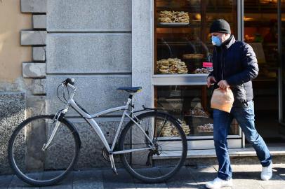 A customer wearing a protective respiratory mask leaves a bakery in Codogno, southeast of Milan, on February 22, 2020. - An Italian man became the first European to die after being infected with the coronavirus on February 21, just hours after 10 towns in the country were locked down following a flurry of new cases. (Photo by Miguel MEDINA / AFP)<!-- NICAID(14428324) -->