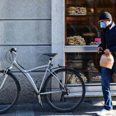 A customer wearing a protective respiratory mask leaves a bakery in Codogno, southeast of Milan, on February 22, 2020. - An Italian man became the first European to die after being infected with the coronavirus on February 21, just hours after 10 towns in the country were locked down following a flurry of new cases. (Photo by Miguel MEDINA / AFP)<!-- NICAID(14428324) -->