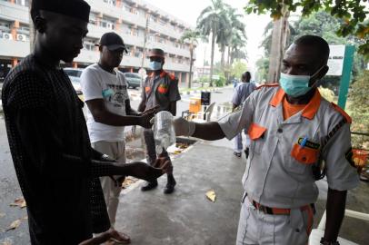 A securityman administers sanitiser to a visitor to a state hospital in Lagos, on February 28, 2020. - Residents of Nigerias economic hub Lagos scrambled for hygiene products after the chaotic megacity of 20 million announced the first confirmed case of new coronavirus in sub-Saharan Africa. Health Minister Osagie Ehanire said in a statement overnight that the infected person was an Italian citizen who flew in from Milan, at the heart of Europes largest outbreak, earlier this week. (Photo by PIUS UTOMI EKPEI / AFP)<!-- NICAID(14434424) -->