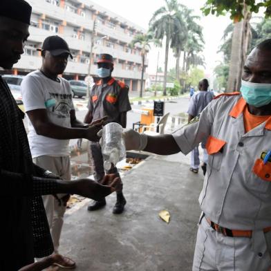 A securityman administers sanitiser to a visitor to a state hospital in Lagos, on February 28, 2020. - Residents of Nigerias economic hub Lagos scrambled for hygiene products after the chaotic megacity of 20 million announced the first confirmed case of new coronavirus in sub-Saharan Africa. Health Minister Osagie Ehanire said in a statement overnight that the infected person was an Italian citizen who flew in from Milan, at the heart of Europes largest outbreak, earlier this week. (Photo by PIUS UTOMI EKPEI / AFP)<!-- NICAID(14434424) -->