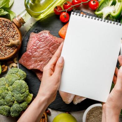 cropped view of woman holding empty notebook above food for ketogenic diet menuPORTO ALEGRE, RS, BRASIL, 25/06/2019- Alimentação saudavel. Dieta. vegetais. verduras. (Foto: LIGHTFIELD STUDIOS  / stock.adobe.com)Fonte: 279814188