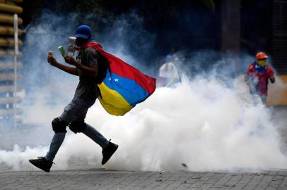 A supporter of Venezuelan opposition leader Juan Guaido shoots back a tear gas canister shot by security forces during clashes while marching to the National Assembly, in Caracas on March 10, 2020. (Photo by Federico Parra / AFP)<!-- NICAID(14446576) -->