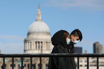 Pedestrians wearing face masks walk along a bridge with St Paul's Cathedral in the background in London on March 12, 2020. - The British government was expected Thursday to implement the second phase of its plan to deal with the coronavirus outbreak but rejected calls for parliament to be suspended after an MP tested positive. (Photo by ISABEL INFANTES / AFP)<!-- NICAID(14448926) -->