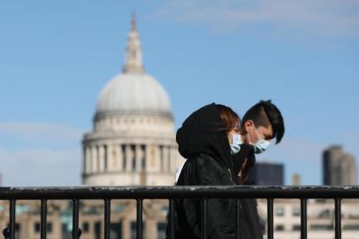 Pedestrians wearing face masks walk along a bridge with St Pauls Cathedral in the background in London on March 12, 2020. - The British government was expected Thursday to implement the second phase of its plan to deal with the coronavirus outbreak but rejected calls for parliament to be suspended after an MP tested positive. (Photo by ISABEL INFANTES / AFP)<!-- NICAID(14448926) -->