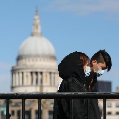 Pedestrians wearing face masks walk along a bridge with St Pauls Cathedral in the background in London on March 12, 2020. - The British government was expected Thursday to implement the second phase of its plan to deal with the coronavirus outbreak but rejected calls for parliament to be suspended after an MP tested positive. (Photo by ISABEL INFANTES / AFP)<!-- NICAID(14448926) -->