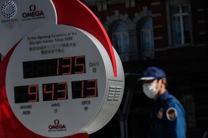 A security guard wearing a face mask walks in front of the Olympic countdown clock outside  Tokyo station on March 11, 2020. - Japan and Olympic organisers are at pains to insist this summers Games in Tokyo are on, despite the new coronavirus outbreak. (Photo by Philip FONG / AFP)<!-- NICAID(14449448) -->