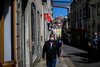 A man wearing a face mask walks at Chiado in Lisbon on March 14, 2020. - Portugal has so far reported 169 confirmed cases of coronavirus, far below neighboring Spain, where there are over 5,700 cases and dozens of fatalities. The governmnet has ordered schools to close next week due to the outbreak of the deadly virus, ordered nightclubs to close and imposed restrictions on the number of people who can visit restuarants. It has also announced that cruise ships would not be allowed to disembark passengers except those living in Portugal. (Photo by PATRICIA DE MELO MOREIRA / AFP)<!-- NICAID(14451820) -->