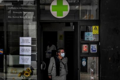 A woman wearing a face mask exits a pharmacy bearing warnings at the entrance about the end of stocks of masks, gloves and alcohol in downtown Lisbon on March 14, 2020. - Portugal has so far reported 169 confirmed cases of coronavirus, far below neighboring Spain, where there are over 5,700 cases and dozens of fatalities. The governmnet has ordered schools to close next week due to the outbreak of the deadly virus, ordered nightclubs to close and imposed restrictions on the number of people who can visit restuarants. It has also announced that cruise ships would not be allowed to disembark passengers except those living in Portugal. (Photo by PATRICIA DE MELO MOREIRA / AFP)<!-- NICAID(14451817) -->