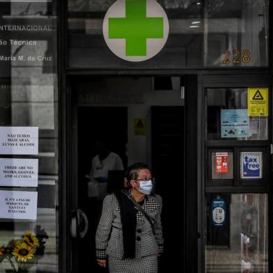 A woman wearing a face mask exits a pharmacy bearing warnings at the entrance about the end of stocks of masks, gloves and alcohol in downtown Lisbon on March 14, 2020. - Portugal has so far reported 169 confirmed cases of coronavirus, far below neighboring Spain, where there are over 5,700 cases and dozens of fatalities. The governmnet has ordered schools to close next week due to the outbreak of the deadly virus, ordered nightclubs to close and imposed restrictions on the number of people who can visit restuarants. It has also announced that cruise ships would not be allowed to disembark passengers except those living in Portugal. (Photo by PATRICIA DE MELO MOREIRA / AFP)<!-- NICAID(14451817) -->