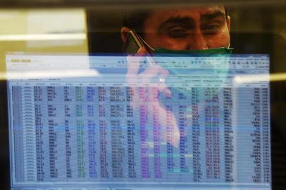 A stockbroker wearing a facemask amid concerns over the spread of the COVID-19 novel coronavirus, watches the share prices during a trading session at the Pakistan Stock Exchange (PSX) in Karachi on March 16, 2020. (Photo by Asif HASSAN / AFP)<!-- NICAID(14452534) -->