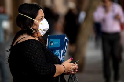 A pedestrian wears a face mask as a precautionary measure against the spread of the new coronavirus, COVID-19, near La Moneda Presidential Palace in Santiago, on March 16, 2020. - Chile announced the closure of all borders after the number of people infected with coronavirus in the country duplicated in the last 24 hours, from 75 to 155, President Sebastian Pinera reported on Monday. (Photo by Martin BERNETTI / AFP)<!-- NICAID(14453013) -->