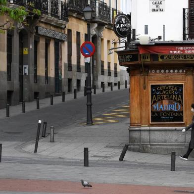 A woman walks the empty street on March 17, 2020 during a lockdown in Madrid as part of the countrys fight against the spread of the coronavirus, COVID-19. - The Spanish government will allocate up to 100 billion euros ($110 billion) for loan guarantees to businesses to buffer the economy from the damage caused by the coronavirus outbreak, Prime Minister Pedro Sanchez said today. Spain confirmed nearly 2,000 new cases of COVID-19, sending the total spiralling past 11,000, with 491 deaths, the health ministry said. (Photo by GABRIEL BOUYS / AFP)<!-- NICAID(14454221) -->