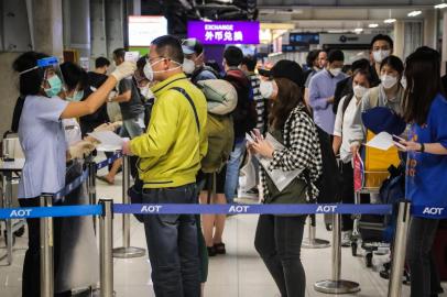 A health official checks the temperature of an incoming passenger during a health assessment at a checkpoint for people flying in from a list of countries and territories that include China, Hong Kong, Macau, South Korea, Iran and Italy, as a precautionary measure against the spread of the COVID-19 coronavirus at Suvarnabhumi Airport in Bangkok on March 9, 2020. (Photo by VIVEK PRAKASH / AFP)<!-- NICAID(14452733) -->