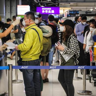 A health official checks the temperature of an incoming passenger during a health assessment at a checkpoint for people flying in from a list of countries and territories that include China, Hong Kong, Macau, South Korea, Iran and Italy, as a precautionary measure against the spread of the COVID-19 coronavirus at Suvarnabhumi Airport in Bangkok on March 9, 2020. (Photo by VIVEK PRAKASH / AFP)<!-- NICAID(14452733) -->