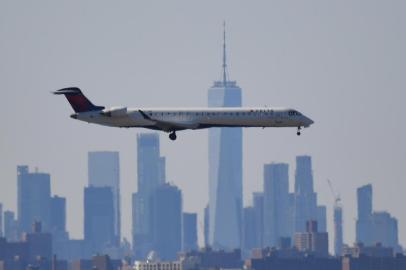 Avião da Delta Airlines sobreboa Manhattan. Cerca de 10 mil funcionários aceitaram acordo para demissão voluntária(FILES) In this file photo taken on March 15, 2020 A plane from Delta airline is seen above the skyline of Manhattan before it lands at JFK airport in New York City. - Fears of massive bankruptcies and calls for emergency bailouts swept global airlines March 17, 2020 as a top US official warned the coronavirus crisis threatens the industry even more than the September 11 attacks, which saw US airspace shut down entirely. Italy moved to take over insolvent Alitalia while Sweden and Denmark offered 275 million euros in guarantees to help prop up Scandinavian carrier SAS. (Photo by Johannes EISELE / AFP)<!-- NICAID(14455344) -->