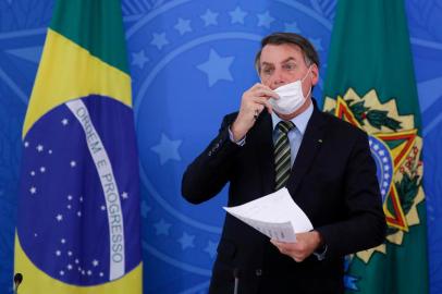  Brazilian President Jair Bolsonaro takes off his face mask during a press conference regarding the COVID-19, coronavirus pandemic at the Planalto Palace, Brasilia on March 18, 2020. (Photo by Sergio LIMA / AFP)Editoria: HTHLocal: BrasíliaIndexador: SERGIO LIMASecao: governmentFonte: AFPFotógrafo: STR<!-- NICAID(14455486) -->