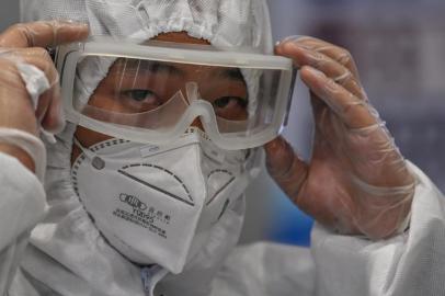 A member of the airport security wearing protective gear as a preventive measure against the COVID-19 coronavirus outbreak monitors passengers as they exit following their arrival at Shanghai Pudong International Airport in Shanghai in March 26, 2020. (Photo by Hector RETAMAL / AFP)<!-- NICAID(14461758) -->