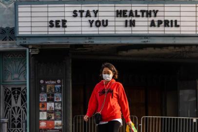 (FILES) In this file photo taken on March 21, 2020, awoman walks wearing a mask to protect herself from the novel coronavirus (COVID-19) in front of a closed theater in Koreatown, Los Angeles. - The economic shutdown caused by the coronavirus pandemic sparked an explosion of Americans filing for unemployment benefits, surging to 3.3 million last week -- the highest number ever recorded, the Labor Department reported on March 26, 2020. (Photo by Apu GOMES / AFP)<!-- NICAID(14461908) -->