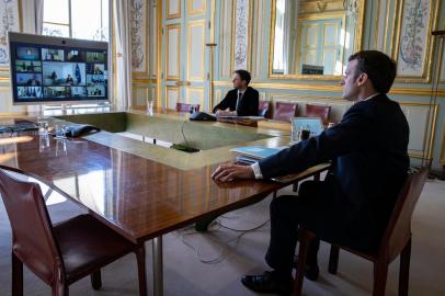  French President Emmanuel Macron (R) attends a video conference call with members of the European Council at the Elysee Palace in Paris, on March 26, 2020, to discuss coordination of EU efforts to tackle the outbreak of COVID-19 (novel coronavius), as well as other issues, including foreign affairs, digital policy and enlargement. - EU leaders will try on March 26 to unify their scattershot response to the COVID-19 epidemic, after hardest-hit Spain, France and Italy called for joint borrowing to share the economic burden. Hundreds of millions of the blocs citizens are holed up at home, during lockdowns imposed to help slow the pandemic that has killed more than 20,000 Europeans and crippled business life. (Photo by Ian LANGSDON / POOL / AFP)Editoria: POLLocal: ParisIndexador: IAN LANGSDONSecao: diplomacyFonte: POOLFotógrafo: STF<!-- NICAID(14461945) -->