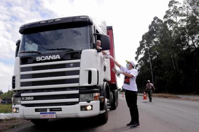  CAXIAS DO SUL, RS, BRASIL, 28/03/2020 - Protegidos com luvas e náscaras, grupo de voluntários distribuem marmitas aos caminhoneiros, que enfrentam dificuldades para se alimentar, com decreto que não permite abertura de restaurantes. A ação ocorreu na Rota do Sol, próximo ao viaduto torto, e contou com apoio da Brigada Militar. (Marcelo Casagrande/Agência RBS)<!-- NICAID(14463799) -->