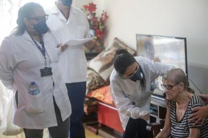  PORTO ALEGRE, RS, BRASIL - 2020.04.01 - Vacinação de gripe a domicílio para idosos. Pessoas com mais de 80 anos que já acessaram unidades de saúde da Secretaria Municipal de Saúde (SMS) são vacinadas contra a influenza em casa a partir desta quarta-feira, 1º de abril. Na imagem: Apartamento de Paulo Martins, 83 e Garcinda Vieira Martins, 87. Cuidadora que também tomou vacina, Karina Grassi dos Santos. (Foto: André Ávila/Agencia RBS)Indexador: Andre Avila<!-- NICAID(14466701) -->