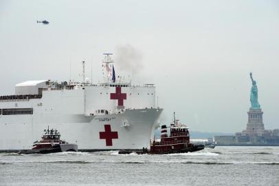  The USNS Comfort medical ship moves up the Hudson River past the Statue of Liberty as it arrives on March 30, 2020 in New York. - A military hospital ship arrived in New York Monday as Americas coronavirus epicenter prepares to fight the peak of the pandemic that has killed over 2,500 people across the US. The navys 1,000-bed USNS Comfort entered a Manhattan pier around 10:45 am (1545 GMT). It will treat non-virus-related patients, helping to ease the burden of hospitals overwhelmed by the crisis. (Photo by Bryan R. Smith / AFP)Editoria: HTHLocal: New YorkIndexador: BRYAN R. SMITHSecao: healthcare policyFonte: AFPFotógrafo: STR<!-- NICAID(14464921) -->