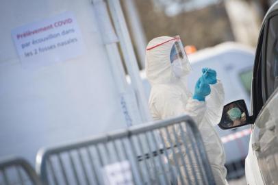 A woman at the wheel of her car undergoes a drive-through swabbing test for coronavirus on April 3, 2020 in Saint-Nazaire, western France, during the countrys lockdown aimed at curbing the spread of the COVID-19 infection, caused by the novel coronavirus. (Photo by Loic VENANCE / AFP)<!-- NICAID(14468395) -->