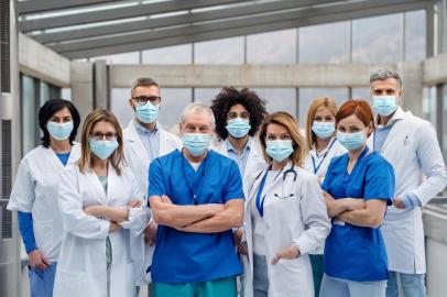 Group of doctors with face masks looking at camera, corona virus concept.A group of doctors with face masks looking at camera, corona virus concept.Fonte: 322150086<!-- NICAID(14472268) -->