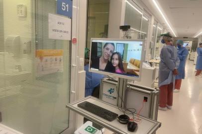 Sabrina Ramos da Silva e a filha Maria Luísa conectadas, por meio de videochamada, a um computador localizado no Centro de Terapia Intensiva do Hospital Moinhos de Vento, em Porto Alegre. Mãe e filha fizeram uma visita virtual ao paciente Leonardo Ramos Scharlau, primo de Sabrina e padrinho de Maria Luísa, que foi internado na instituição com suspeita de infecção por coronavírus.<!-- NICAID(14473082) -->