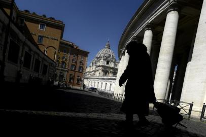 A homeless person pulling a trolley walks along The Vaticans colonnades on April 1, 2020 at the limit between Italy and The Vatican, with St. Peters basilica in background, during the countrys lockdown aimed at curbing the spread of the COVID-19 infection, caused by the novel coronavirus. (Photo by Filippo MONTEFORTE / AFP)<!-- NICAID(14468292) -->