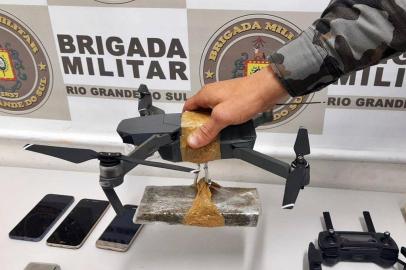 release: O Serviço de Inteligência da Brigada Militar frustrou a ação de criminosos que entregariam drogas na Penitenciária Estadual de Caxias do Sul, na localidade do Apanhador.O flagrante ocorreu tarde desta quarta-feira (15/04), quando PMs monitoravam o entorno da casa prisional aguardando a confirmação do alerta de tráfico de entorpecentes. Por volta das 16h o veículo suspeito se aproximou e foi abordado pelos policiais.  Durante a revista foram apreendidos celulares, balança de precisão, 400g cocaína, sete tijolos de maconha** e um drone, avaliado em  cerca de 7 mil reais que seria usado para transportar a droga.<!-- NICAID(14478356) -->