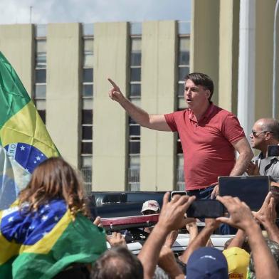 Brazilian President Jair Bolsonaro speaks after joining his supporters who were taking part in a motorcade to protest against quarantine and social distancing measures to combat the new coronavirus outbreak in Brasilia on April 19, 2020. (Photo by EVARISTO SA / AFP)<!-- NICAID(14481427) -->