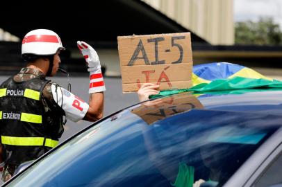  A supporter of Brazilian President Jair Bolsonaro holds a sign demanding for military intervention (AI-5) from a car during a motorcade against quarantine and social distancing measures imposed by governors and mayors to combat the new coronavirus outbreak in Brasilia on April 19, 2020. (Photo by Sergio LIMA / AFP)Editoria: HTHLocal: BrasíliaIndexador: SERGIO LIMASecao: diseaseFonte: AFPFotógrafo: STR<!-- NICAID(14481584) -->