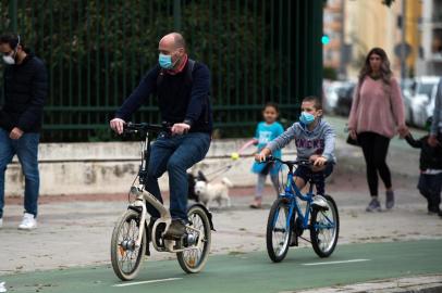 775506872A man and a child wearing face masks, ride bicycles in Seville, on April 26, 2020 during a national lockdown to prevent the spread of the COVID-19 disease. - After six weeks stuck at home, Spains children were being allowed out today to run, play or go for a walk as the government eased one of the worlds toughest coronavirus lockdowns. Spain is one of the hardest hit countries, with a death toll running a more than 23,000 to put it behind only the United States and Italy despite stringent restrictions imposed from March 14, including keeping all children indoors. Today, with their scooters, tricycles or in prams, the children accompanied by their parents came out onto largely deserted streets. (Photo by CRISTINA QUICLER / AFP)Editoria: HTHLocal: SevilleIndexador: CRISTINA QUICLERSecao: diseaseFonte: AFPFotógrafo: STR<!-- NICAID(14486185) -->