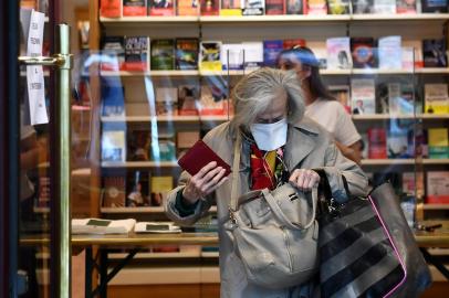 An elderly person wearing a face mask walks out of a bookstore after picking up their order in Neuilly-sur-Seine, on April 28, 2020, on the 43rd day of a lockdown in France aimed at curbing the spread of the COVID-19 disease, caused by the novel coronavirus. - Bookshops are among the hardest hit by the lockdown measures put in place since March 17. Until stores reopen on May 11, many establishments have already set up a click & collect service to provide customers with a book they have ordered online. (Photo by FRANCK FIFE / AFP)<!-- NICAID(14487533) -->