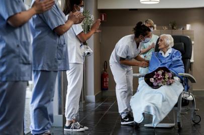 Medical workers clap as Belgian 100 year-old patient Julia Dewilde leaves the Bois de lAbbaye hospital (CHBA) in Seraing, after being succesfully treated for COVID-19, the disease caused by the novel coronavirus, on April 29, 2020. (Photo by Kenzo TRIBOUILLARD / AFP)