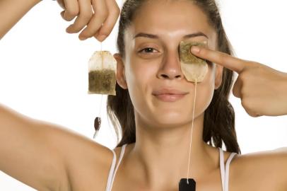  Young smiling woman posing with tea bag on her eye on white backgroundFonte: 284810688<!-- NICAID(14489842) -->