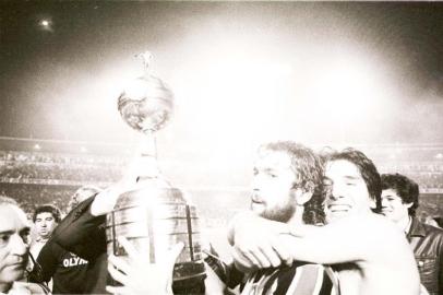 CRÉDITO: Adolfo Alves - Agência RBSA imagem acima, com ligeiras variações, aconteceu duas vezes em 1983.A primeira foi esta mesmo: De León ergue a taça da Libertadores no Olímpicoapós a vitória sobre o Peñarol, abraçado com alegria juvenil pelo herói RenatoPortaluppi. A outra viria meses depois, na final contra o Hamburgo, em Tóquio,quando o Grêmio esculpiu o nome na galeria dos campeões do mundo. A partirde hoje, quando o time do técnico Mano Menezes entrar em campo contra o Cerro Porteño, no Paraguai, gremistas do país inteiro têm todo o direito de sonhar com uma reprise de 1983. Pode ser que dê tudo errado, claro que pode, o futebol está cheio de casos assim. Mas o fato é que o Grêmio fez tudo certo para disputar a Libertadores com chances de ganhá-la. Manteve a comissão técnica, agregou experiência e qualidade ao grupo do ano passado e, o mais importante, colheu os frutos da reestruturação das categorias de base. Lucas, Carlos Eduardo e Everton estão aí. O Grêmio conquistou o direito de imaginar uma nova versão de si mesmo, quem sabe com Tcheco no lugar de De León, e Lucas, no de Renato.#PÁGINA:53<!-- NICAID(1921372) -->